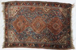 A red ground rug with three central medallions in a geometric pattern,