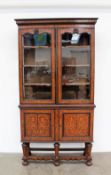 A 19th century continental marquetry display cabinet with a moulded cornice above a pair of glazed