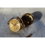 An 18ct yellow gold key wound open faced fob watch with Roman numerals and a floral decorated gilt
