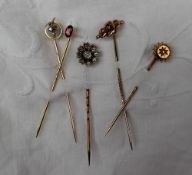 A three stone diamond stick pin together with four other stick pins