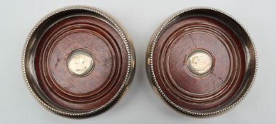 A pair of Elizabeth II silver bottle coasters, with a beaded rim and wooden base, Birmingham, 1994,