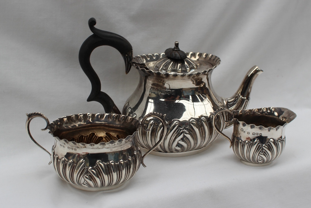 A late Victorian silver three piece tea set, with a scrolling base, Chester 1899, 1900,