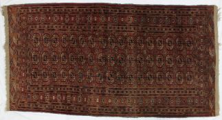A red ground Turkoman style rug, with multiple guls to the centre,