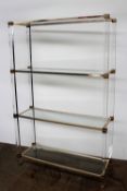 Pierre Vandel, Paris - A glass, perspex and gilt metal shelving unit, with four rectangular shelves,