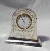 A silver framed desk clock of domed shape engraved with swags and leaves,