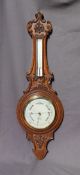 A carved oak aneroid barometer, with a mercury thermometer, the silvered dial inscribed R Bailey,