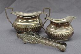 A late Victorian silver cream jug and twin handled sugar basin, with a gadrooned edge and body,