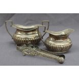 A late Victorian silver cream jug and twin handled sugar basin, with a gadrooned edge and body,