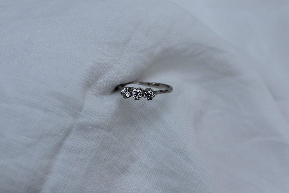 A three stone diamond ring set with three round old cut diamonds each approximately 0.