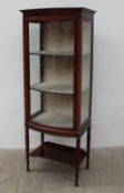 An Edwardian mahogany display cabinet with a bowed front glass door and sides on turned tapering