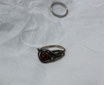 A white metal ring of scrolling naturalistic form set with an amber bead together with a platinum