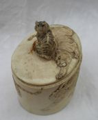 A Japanese ivory box and cover of oval form carved with a tiger finial, the body carved with tigers,