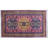 A rug with a pink ground and three large medallions,