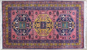 A rug with a pink ground and three large medallions,