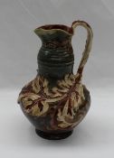 A Mark V Marshall for Doulton Lambeth pottery ewer with a flared rim, with a stylised leaf handle,