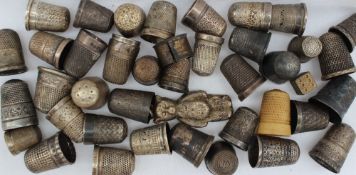 A large collection of silver thimbles, together with a silver teddy bear and other thimbles,