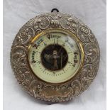 A silver framed barometer, the embossed frame decorated with flower heads and leaves,