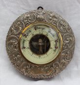 A silver framed barometer, the embossed frame decorated with flower heads and leaves,