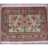 A silk rug, with a vase of flowers and birds to a cream ground,