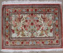 A silk rug, with a vase of flowers and birds to a cream ground,