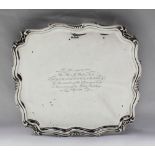 An Edward VII silver salver of square form with a leaf moulded border, on leaf shaped feet,