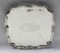 An Edward VII silver salver of square form with a leaf moulded border, on leaf shaped feet,
