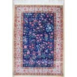 A silk rug, with a dark blue ground decorated with sprays of flower and birds,