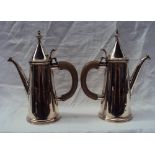 A pair of George VI silver hot water pots with pointed covers and turned finials,