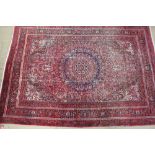 A large red ground rug, with a central medallion, floral spandrels,