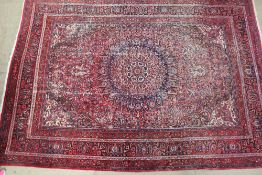 A large red ground rug, with a central medallion, floral spandrels,