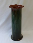 A Linthorpe pottery vase of cylindrical form with a flared rim and mottled green glaze,