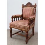 A late Victorian oak elbow chair with a pad upholstered back and seat with spindle supports and