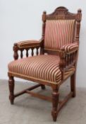 A late Victorian oak elbow chair with a pad upholstered back and seat with spindle supports and