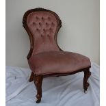 A Victorian walnut framed spoon back nursing chair with a carved rail and button back upholstery