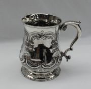 A George II silver baluster tankard, embossed with scrolls, flowerheads and leaves,