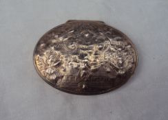 A continental white metal snuff box of oval form, the lid decorated with a central figure,