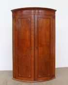 A 19th century oak and mahogany hanging corner cupboard of bowed form with a line inlaid frieze and