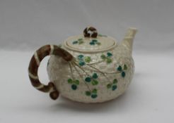 A Belleek porcelain teapot and cover, moulded with a basketweave and shamrock pattern,