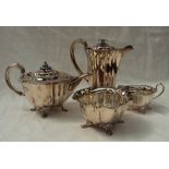 An Edwardian silver three piece tea set, comprising a teapot with enamel decorated finial,