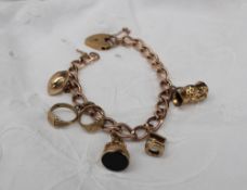 A 9ct yellow gold bracelet set with numerous charms including a toby jug, wishing well, fob,