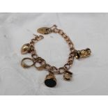 A 9ct yellow gold bracelet set with numerous charms including a toby jug, wishing well, fob,