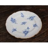 A Nantgarw porcelain plate painted with sprays of cornflower blue flowers to a moulded border and