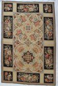 A woolwork rug, decorated with panels of flowers to a cream ground,
