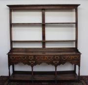 An 18th century South Wales oak dresser, the open rack with a moulded cornice above two shelves,