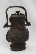 A Chinese bronze 'hu' lidded vessel, with a swing handle decorated with taotie motifs, 18.