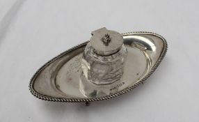 An Edwardian silver desk inkwell, of pointed oval form with a gadrooned edge,