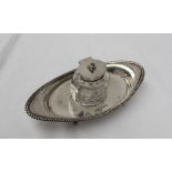 An Edwardian silver desk inkwell, of pointed oval form with a gadrooned edge,