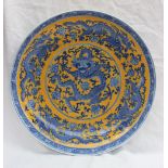 An oriental porcelain charger decorated with dragons and flowers to a yellow ground,