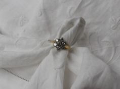 A diamond cluster ring set with seven round brilliant cut diamonds in a daisy formation,