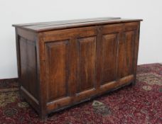 An 18th century oak coffer with a planked top above a four-panel front on stiles, 51.5cm deep x 76.